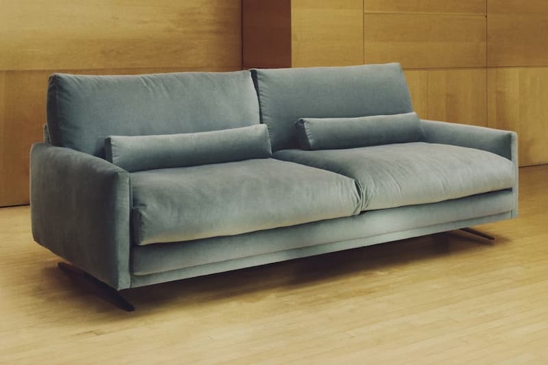 Divano quiet luxury in velluto verde con gambe in acciaio nero